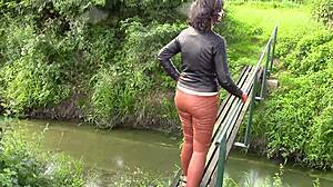 She smokes while wearing cinnamon leather trousers outdoors.