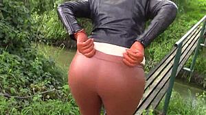 She smokes while wearing cinnamon leather trousers outdoors.